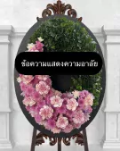 A floral wreath with pink and green flowers and a black sign with Thai text.