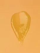 Golden, viscous liquid, like honey or serum, on an orange background.