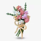 A balloon bouquet with pink, white, and purple flowers tied with a yellow ribbon on a white background.