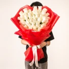A large bouquet of 50 white roses in a red wrap, held by a person.
