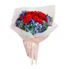 Bouquet of red roses and blue hydrangeas, wrapped in white and pink paper with a cream ribbon.