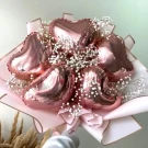 Rose gold heart-shaped balloons with baby's breath in a bouquet.