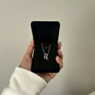 Silver Leo zodiac sign necklace in a black velvet jewelry box held by a hand.