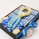 luxury golden gift box featuring 30 neatly rolled banknotes, paired with a spiraled Crown Flower garland and fresh blue blooms