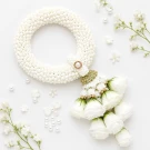Hand-woven jasmine garland with white roses on a shimmering pink fabric.