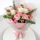 Bouquet of white and pink roses with carnations, eucalyptus, and pink paper wrap, tied with a pink ribbon.