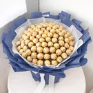 A large bouquet of 100 Ferrero Rocher chocolates, wrapped in dark blue paper with white ribbons.