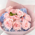 Pink roses and blue hydrangeas in a pink paper wrap.
