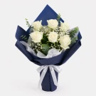 White roses, gypsophila, and eucalyptus in navy blue wrapping paper, tied with a white ribbon.
