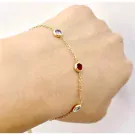 Gold chain bracelet with three bezel-set gemstones: amethyst, ruby, and topaz.