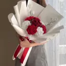 Crocheted bouquet of red and white roses with white accent flowers and red ribbon.