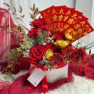 Red roses and gerberas in a white box adorned with red envelopes and gold ingots.