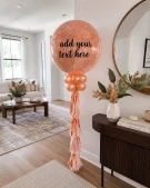 Rose gold glitter balloon with decorated with small balloons and fringe.