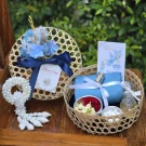 Woven baskets hold blue fabric, flowers, and a jasmine garland, symbolizing Thai New Year traditions.