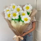 Daisy balloon bouquet with smiley faces and satin ribbon, held by a person.