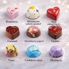 Nine artfully decorated chocolates in a variety of shapes and colors, each with a label.