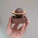 Hand holding a wooden planet oil diffuser with rings, on a wooden base.