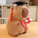 Plush capybara wearing graduation cap and sash, holding diploma.