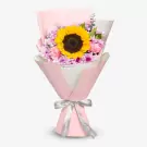 Bouquet of a sunflower surrounded by pink and violet flowers, wrapped in pink paper with a silver ribbon.