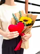 Red heart plush and sunflower bouquet, wrapped in brown paper and tied with red ribbon.