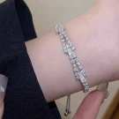 A silver bracelet with baguette-cut and round rhinestones on a wrist.