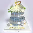 Two-tiered cake decorated with rolled Thai 50 baht banknotes and white flowers.