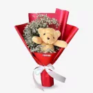 Teddy bear with white dry limonium in red bouquet wrap, tied with white ribbon.