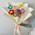 Graduation bouquet with a plush otter wearing a cap and smiling plush flowers.
