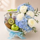 A gift box with fruit, milk, juice, and a bouquet of white roses and blue hydrangeas.