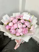A lush bouquet of 30 pink peonies, artfully arranged and tied with a peach ribbon.