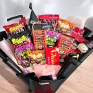 Halloween snack bouquet with assorted candies, wrapped in black paper and adorned with a witch's hat.