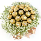Ferrero Rocher chocolates and white gypsophila flowers arranged in a bouquet, tied with a ribbon.