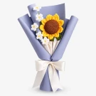 Crocheted sunflower and white blossoms in blue paper with ivory ribbon.