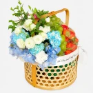 Woven basket with strawberries, green apples, and a blue and white flower arrangement.