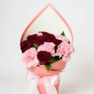 Bouquet of red roses and pink carnations in pink paper wrapping with a pink bow.