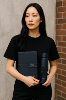 Woman in black t-shirt holding a personalized navy blue notebook and tumbler.