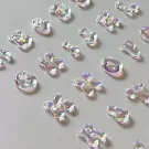 Iridescent acrylic letter charms arranged on a gray surface.