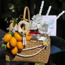 Songkran gift basket with golden fruit, clay garland, lotus flowers, and decorative pearls.