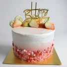 Pink ombre Tres Leches cake with strawberries and "Happy Birthday" topper.