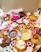 A box overflowing with cookies, brownies, marshmallows, and dips, perfect for a party.