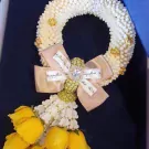 Golden Glow Malai: White flower garland with yellow roses, gold bow, and jeweled center.