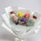 Graduation bouquet of colorful pom-pom "flowers" in graduation caps, surrounded by baby's breath.