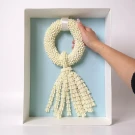 A hand holding a white jasmine garland in a light blue box.