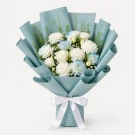 Bouquet of white roses and blue hydrangeas wrapped in light blue paper with a white ribbon.