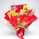 Red and gold Lunar New Year gift arrangement with red envelopes, wheat stalks, and a lucky cat.