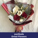 A bouquet of dried red and cream flowers, wrapped in dark red paper.