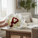A bouquet of white and red roses arranged to form the letter "P" on a wooden table.
