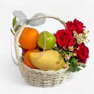 Fruit basket with oranges, mango, apples, red roses, and daisies, tied with a silver ribbon.