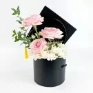 Black graduation box with pink roses, white mums, and a yellow tassel.