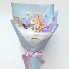 A bouquet of colorful velvet wire flowers and hearts wrapped in light blue paper and tied with a pink ribbon.
